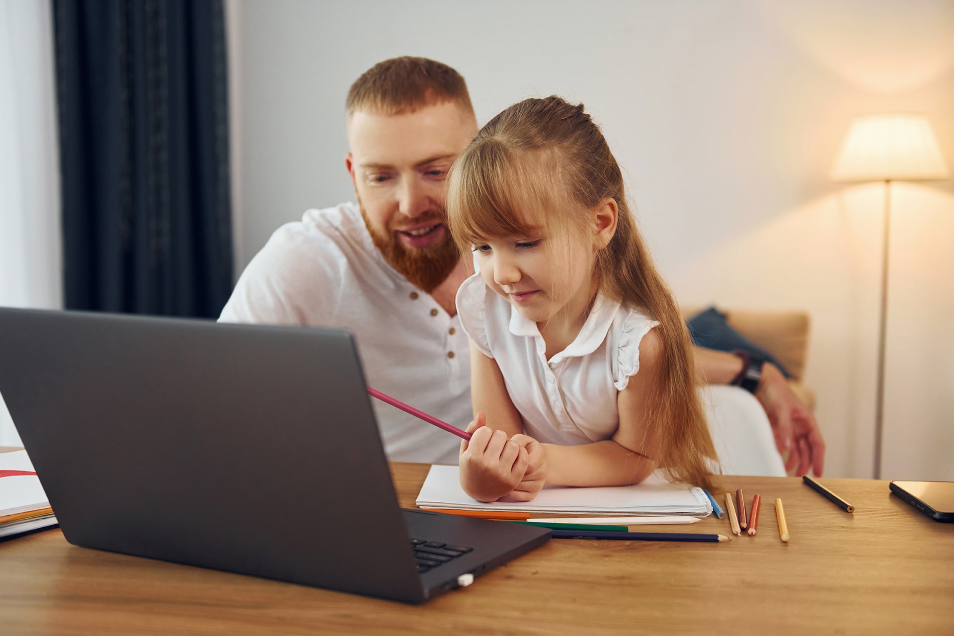 photo of a father helping daughter with homework on a laptop